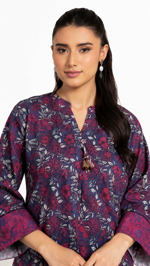 A woman modeling a navy blue and magenta floral printed kurta with a split neckline and tassel tie, set against a plain white background.
