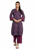 A woman modeling a traditional Indian outfit consisting of a dark purple and pink floral printed kurta with matching printed pants, styled with white slide sandals against a plain white background.