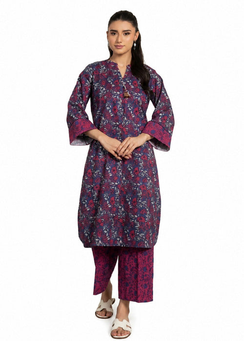 A woman modeling a traditional Indian outfit consisting of a dark purple and pink floral printed kurta with matching printed pants, styled with white slide sandals against a plain white background.