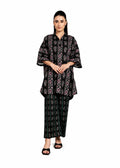 A woman modeling a black two-piece traditional outfit with intricate multicolor floral and paisley patterns, consisting of a short-sleeved tunic and matching wide-leg pants, against a plain white background.