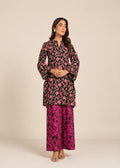 A woman modeling a two-piece floral printed outfit consisting of a black long-sleeve kurta with pink and green floral patterns and matching wide-leg trousers in bright pink and black.