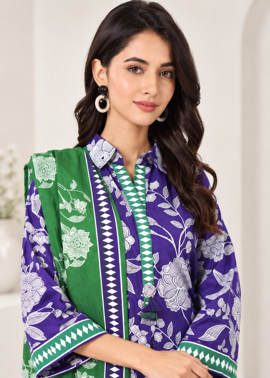 A woman modeling a purple and green printed traditional outfit with a matching green dupatta, featuring white floral patterns and geometric borders.