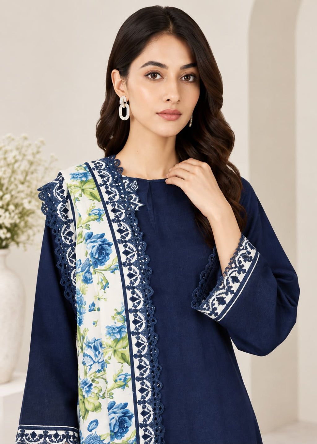A woman modeling a navy blue kurta with a floral printed dupatta featuring blue and green flowers on a cream background, with white and navy lace trim.