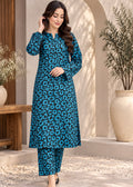 A woman modeling a teal blue and black leopard-print kurta set with matching pants, standing in a styled outdoor courtyard setting.