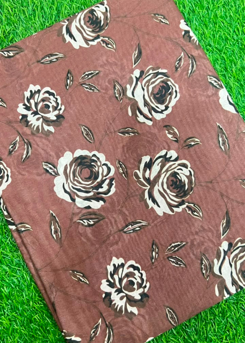 A brown fabric with a white and black rose pattern, laid flat on a green grass-like surface.