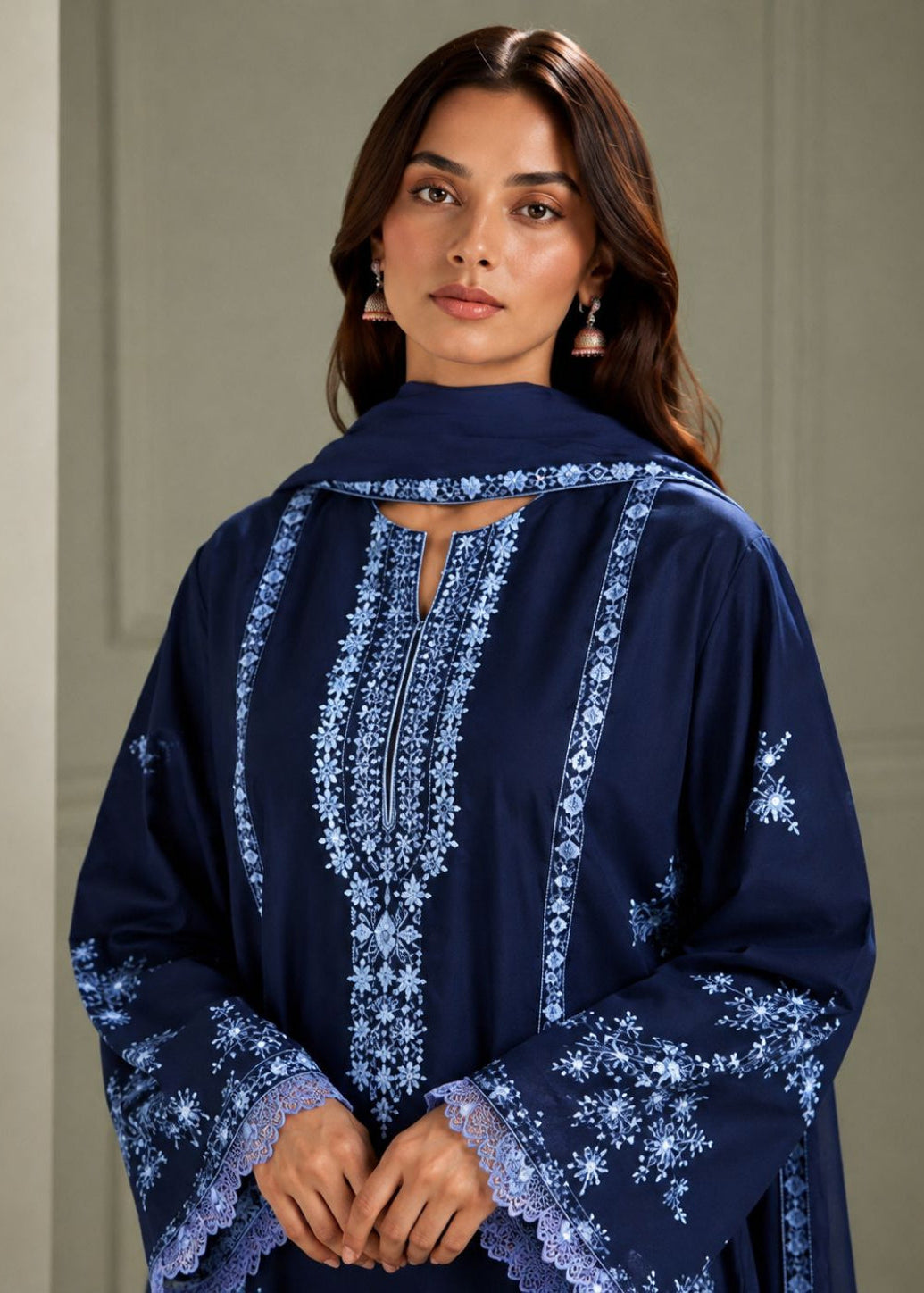 A woman wearing a navy blue embroidered kurta with intricate white and light blue floral embroidery on the front, sleeves, and collar, paired with a matching navy dupatta.