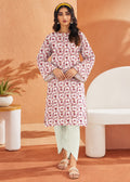 A woman models a long-sleeve kurta with a pink and white floral pattern, paired with light sage green pants and beige sandals, standing in a modern, warm-toned studio setting.