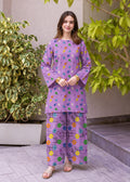 A woman modeling a purple two-piece kurta set with colorful floral prints, standing outdoors on a paved walkway with green plants in the background.