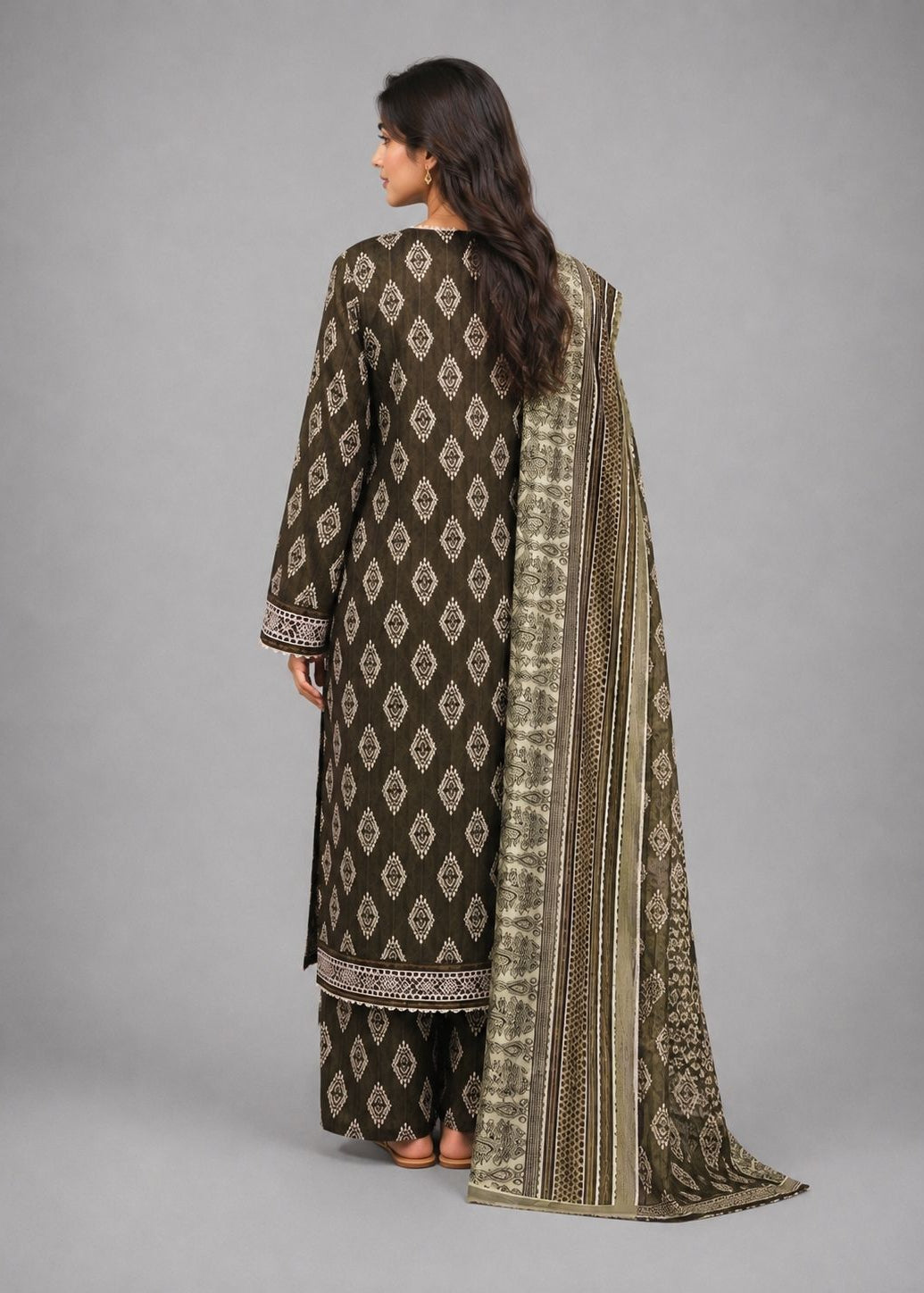 A woman shown from the back wearing a dark brown traditional outfit with beige geometric patterns and a matching patterned dupatta, photographed against a solid gray studio background.