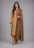 A woman modeling a traditional Indian salwar kameez suit set in beige and brown with intricate block prints and a matching dupatta, photographed against a solid gray studio background.