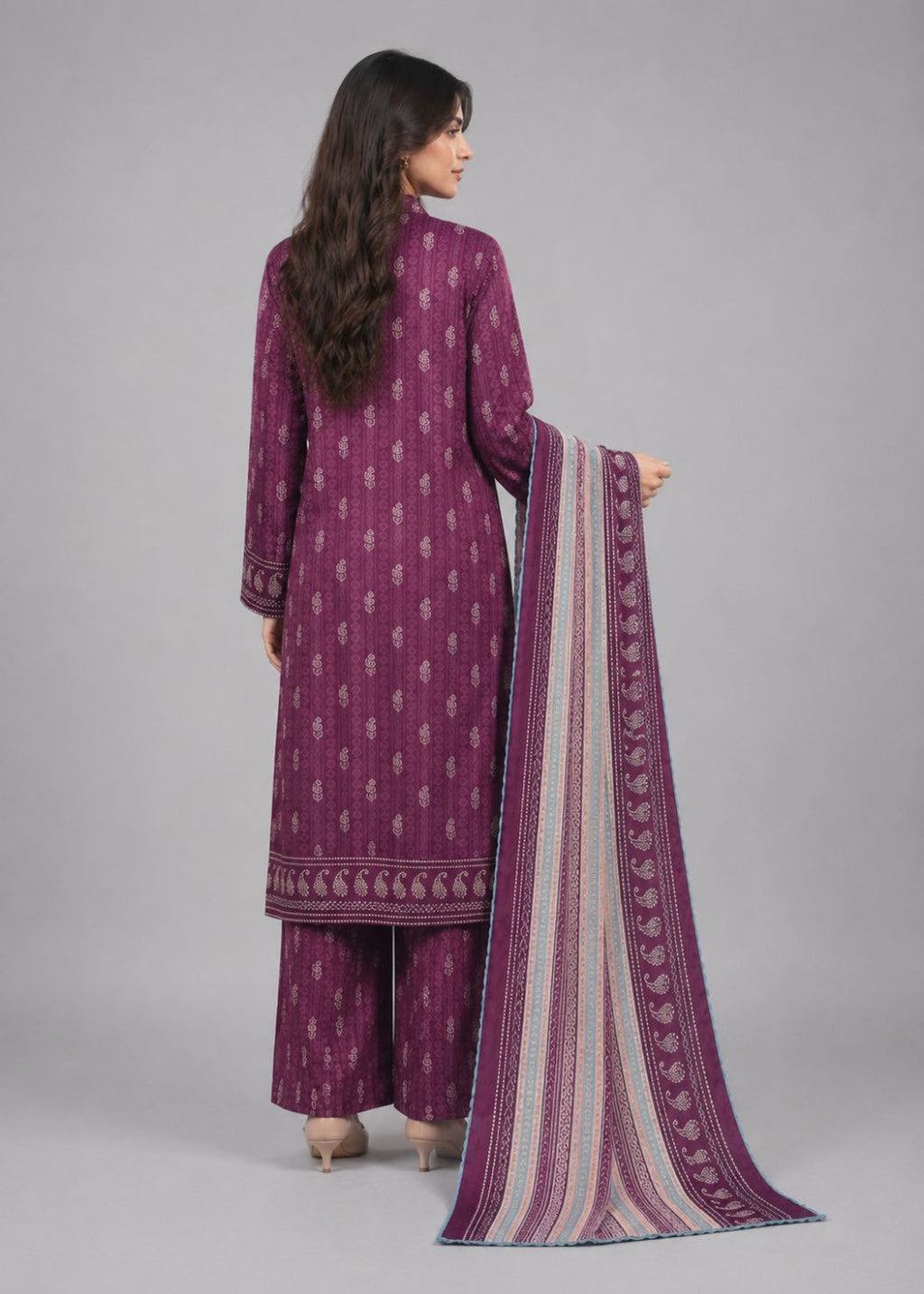 A woman shown from the back wearing a purple traditional outfit with matching patterned pants and holding a striped dupatta with purple borders, against a plain gray studio background.