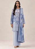 A woman modeling a light blue and white printed traditional outfit with a matching dupatta, consisting of a printed kurta, light blue pants, and a blue patterned scarf, set against a plain beige studio background.