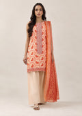 A woman modeling a traditional Indian salwar kameez suit set. The set features a sleeveless cream-colored kurta with orange and red floral embroidery, paired with light beige wide-leg trousers and a matching orange patterned dupatta, set against a plain beige studio background.