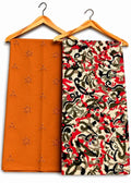 Two folded fabric pieces hanging on wooden hangers against a plain white background. The left piece is a solid burnt orange with small embroidered floral motifs.
