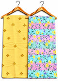 Two folded fabric pieces hanging on wooden hangers against a white background. The left fabric is pale yellow with small embroidered floral motifs.