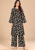 A woman modeling a black and beige abstract leaf-patterned kurta set with matching wide-leg pants, standing against a solid beige studio background.