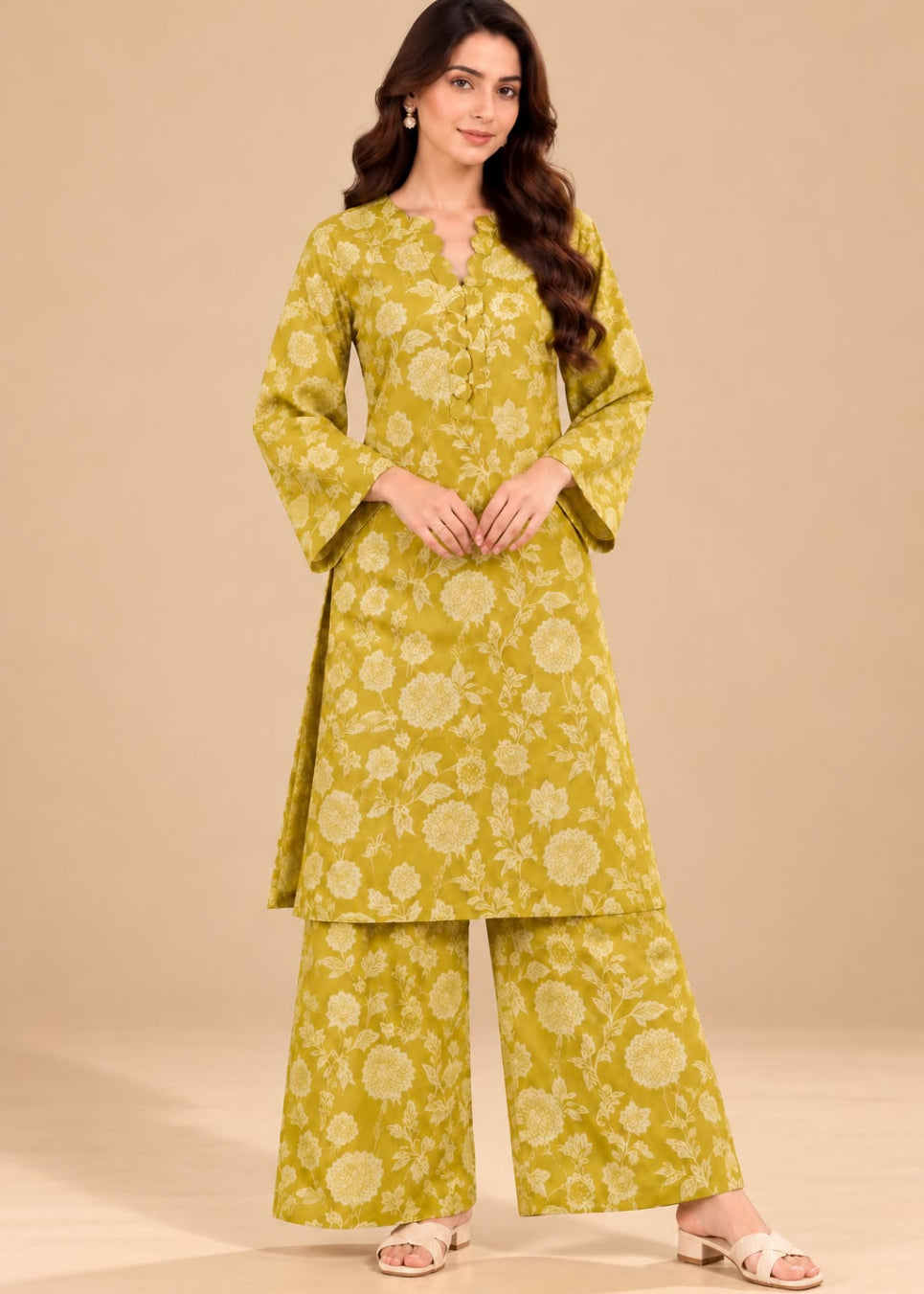 A woman modeling a yellow-green floral printed kurta set with matching wide-leg pants, standing against a solid beige studio background.