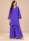 A woman modeling a vibrant royal blue two-piece kurta set with a hot pink abstract floral pattern, set against a solid beige studio background.