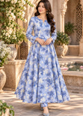 A woman models a long-sleeved light blue and white floral printed Anarkali gown in an outdoor courtyard setting with stone arches and potted plants.