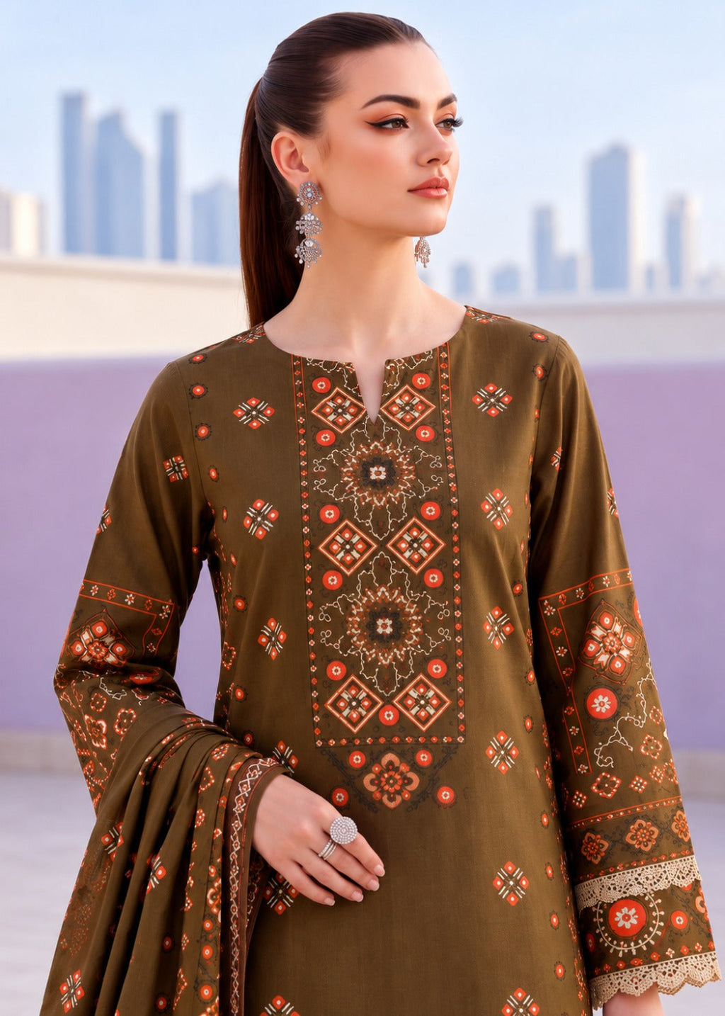 A woman modeling a brown ethnic kurta with intricate orange and beige geometric embroidery, paired with a matching dupatta, set against a blurred cityscape background.