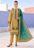 A woman models a traditional three-piece salwar kameez suit in mustard yellow and teal green. The kurta features intricate green printed motifs and a matching green border, paired with solid yellow trousers and a teal dupatta with a gold border and traditional print.