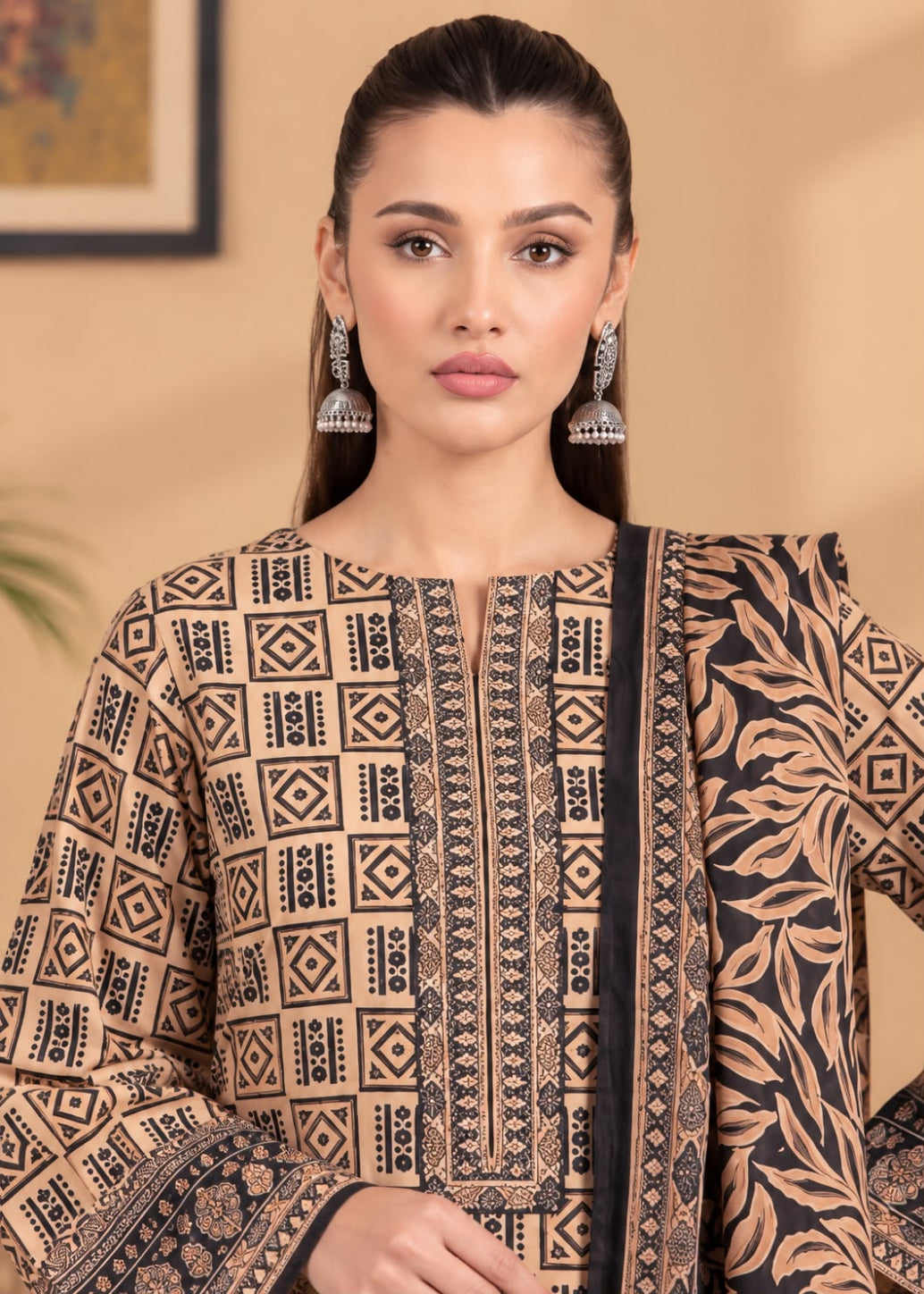 A woman modeling a beige and black printed ethnic kurta with matching printed dupatta, featuring geometric patterns on the front and a leafy print on the side.