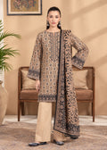 A woman models a traditional three-piece salwar kameez suit in a warm beige tone with intricate black and brown geometric patterns, paired with straight-leg trousers and a matching printed dupatta, set against a cozy indoor background with a wooden chair and potted plant.