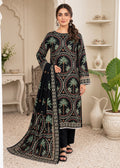 A woman models a black three-piece traditional outfit with intricate multicolor embroidery featuring palm tree motifs, set against an elegant, vintage-style indoor room with arched doorways and shelves.