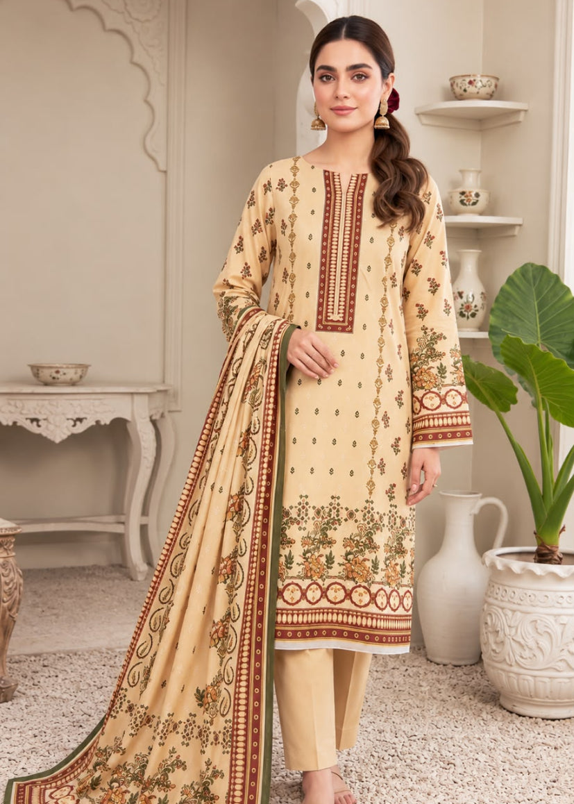 A woman models a traditional three-piece salwar kameez suit in beige with brown and green floral embroidery, paired with matching beige trousers and a coordinating dupatta, set against an elegant indoor backdrop.