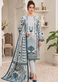 A woman models a traditional three-piece salwar kameez suit in a light blue and white colorway with intricate blue and gray embroidery. The set includes a long-sleeved kameez tunic, matching trousers, and a coordinating dupatta, displayed in a styled indoor room setting.