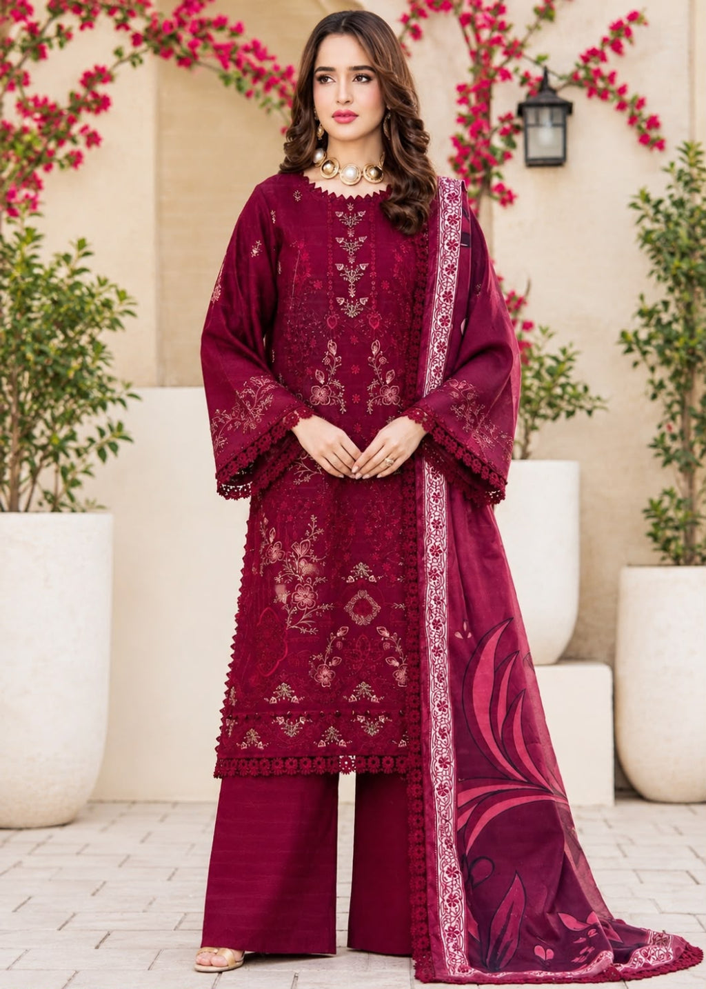 A woman models a traditional three-piece beige ethnic suit with brown floral embroidery and a matching dupatta, set against a beige wooden grid wall background.