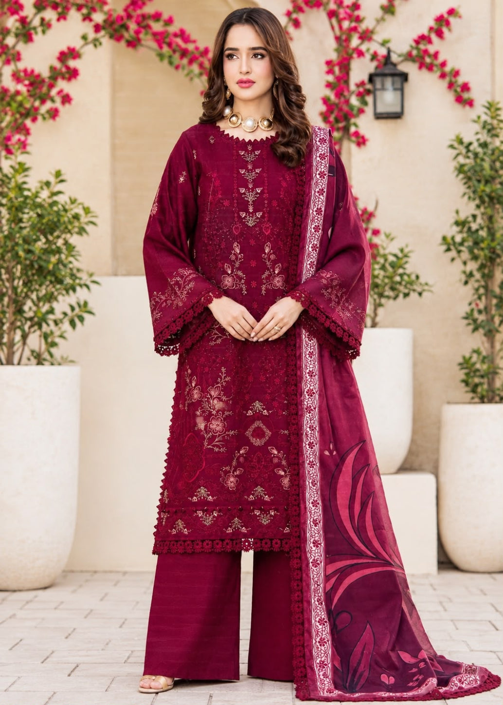 A woman models a traditional three-piece beige ethnic suit with brown floral embroidery and a matching dupatta, set against a beige wooden grid wall background.