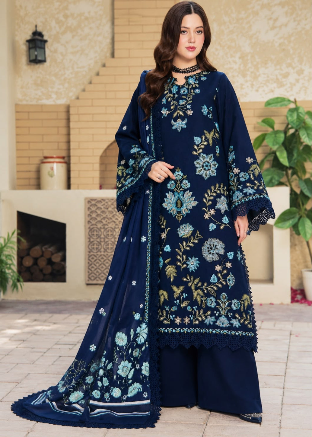 A woman models a traditional three-piece beige ethnic suit with brown floral embroidery and a matching dupatta, set against a beige wooden grid wall background.