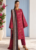 A woman models a traditional Indian salwar kameez suit in a dusty rose pink color with gold floral embroidery, paired with matching trousers and a patterned dupatta, set against a blue paneled door background.
