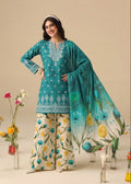 A woman models a traditional South Asian salwar kameez suit set. The set features a teal green kurta with white embroidery, beige wide-leg trousers with a yellow and blue floral print, and a matching teal dupatta with a blue and yellow tulip pattern.