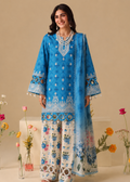 A woman models a traditional three-piece salwar kameez suit. The kurta is bright blue with white embroidery, paired with matching blue and white floral printed wide-leg trousers and a sheer blue dupatta, set against a warm beige background with decorative flowers.