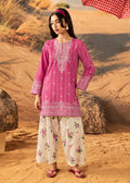 A woman modeling a pink embroidered kurta with white floral pants in a desert setting.