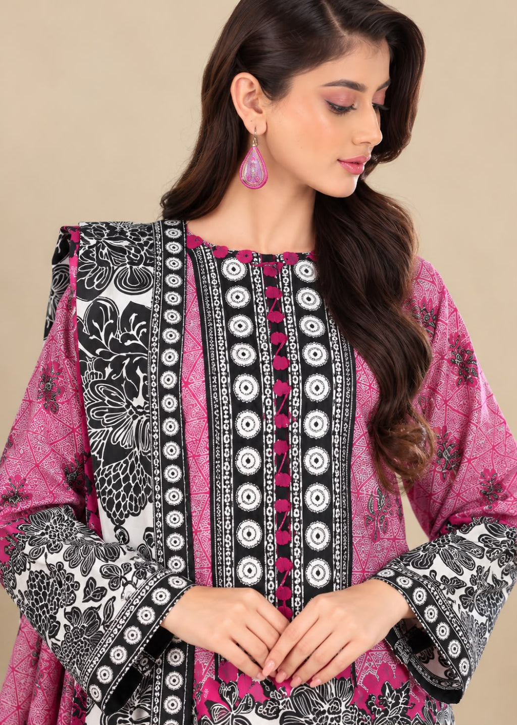 A woman wearing a pink, black, and white printed kurta with detailed geometric and floral patterns, set against a solid beige background.