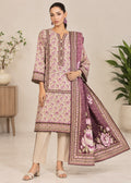 A woman models a traditional three-piece salwar kameez suit set. The set includes a light pink kurta with a purple floral print and gold borders, beige trousers, and a matching purple dupatta with large floral motifs and gold borders.