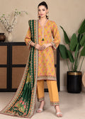 A woman models a traditional three-piece salwar kameez suit set. The set features a mustard yellow printed kurta with pink and green floral motifs, matching yellow trousers, and a dark green printed dupatta with a detailed gold and pink border.