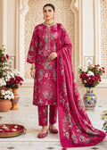 A woman models a traditional Indian salwar kameez suit in a rich magenta pink color with intricate gold and silver floral embroidery, paired with a matching dupatta, set against an ornate beige architectural background with floral arrangements.