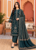 A woman models a dark teal ethnic three-piece suit with intricate gold embroidery, featuring a long kurta, matching pants, and a draped dupatta, set against a warm, traditional Moroccan-style interior background.