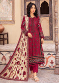 A woman models a traditional Indian salwar kameez suit in a courtyard setting. The outfit features a deep maroon red tunic with floral embroidery, matching maroon pants, and a beige dupatta with red floral motifs and a red border.