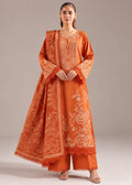 A woman modeling a traditional orange kurta set with intricate beige floral embroidery and a matching dupatta, photographed against a neutral studio background.