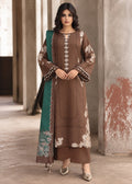A woman models a brown three-piece salwar kameez suit with floral embroidery and a teal green dupatta, standing in a rustic corridor with stone pillars.