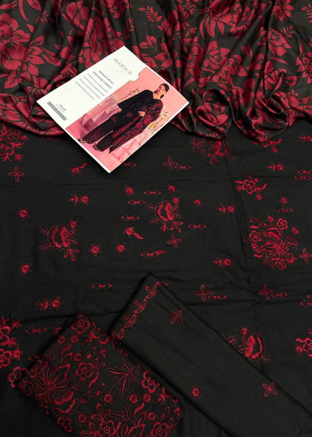 Black fabric with a red floral and butterfly pattern, shown as a styled flat lay with a folded matching fabric piece and a pink printed card.