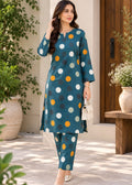 A woman models a teal blue three-piece kurta set with a colorful polka dot pattern, consisting of a long kurta, matching pants, and a small white handbag, set against an outdoor patio backdrop with plants.