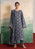 A woman models a three-piece traditional Indian outfit consisting of a gray kurta with white motifs, matching gray trousers, and a navy blue patterned dupatta, set against a scenic painted backdrop.