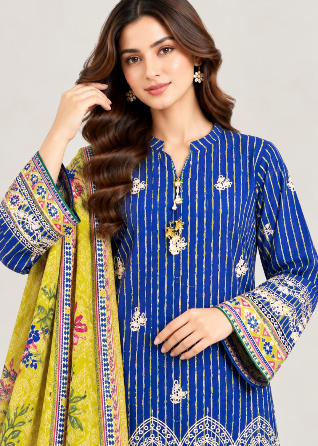 A woman modeling a royal blue kurta with vertical gold stripes and white floral embroidery, paired with a bright yellow-green dupatta featuring colorful floral patterns and embroidered borders.