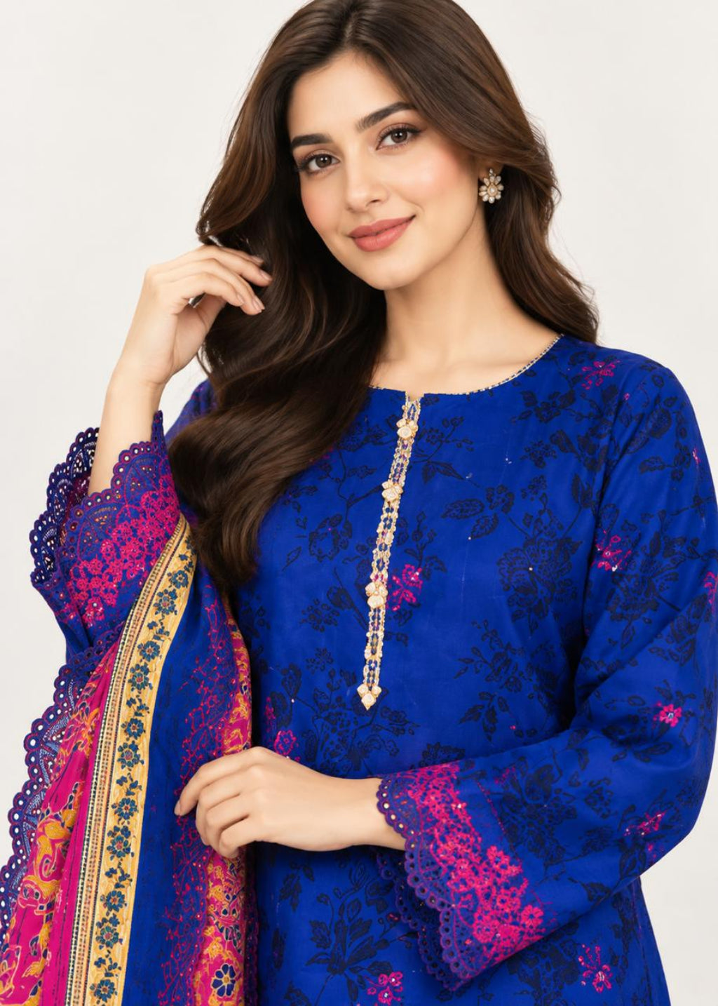 A woman modeling a royal blue embroidered kurta with pink floral accents and a matching pink dupatta with gold border details, set against a plain light gray background.